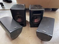 Two pairs of speakers on floor, Pioneer speakers without covers showing speaker cones and bass ports; Infinity speakers with covers with logos visible.