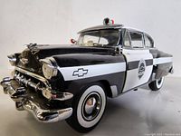Side view of the black and white 1954 Chevrolet Bel Air police car model showing the police badge and chrome details.