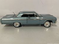 Side view of the metallic blue 1964 Chevrolet Impala model showing detailed side trim and tinted windows