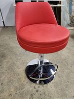 Front view showing red round seat, backrest, chrome pedestal base and footrest