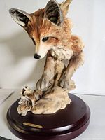 Front view of the fox sculpture showing detailed textured fur and facial features, mounted on wooden base with small nameplate.