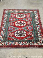 Full top view of square carpet laid flat on concrete floor showing overall design and colors.