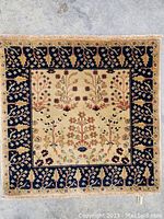 Full view of carpet showing Sarough floral and geometric design, beige center with dark blue border and fringed edges