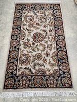 Top-down view of entire rectangular rug with beige field, floral pattern and ivory fringe.