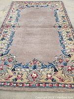 Full view of the beige central field with floral patterned border showing overall condition and color scheme of the rug.