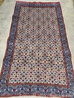 Overhead full view of rug laid on concrete floor showing entire pattern and fringe on ends.