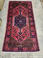 Full front view of entire rug laid flat on concrete floor showing overall design.