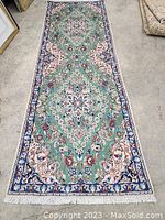 Full-length view of green-field runner with ivory and navy borders laid on concrete floor