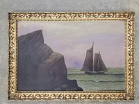 Full view of oil painting in vintage detailed wood frame showing sailing ship and rocky shore scene.