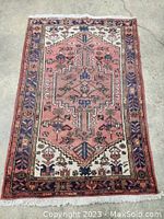 Full view of vintage Persian hand knotted carpet showing entire pattern and fringe edges laid flat on the floor.