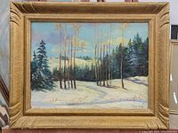 Framed oil painting of winter tree landscape with snow and evergreens, signed by artist.