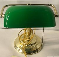 Front angle view showing green glass shade, polished brass base, and pull chain switch.