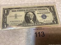 Front view of a 1957 silver certificate one dollar bill with George Washington portrait and blue treasury seal.