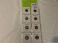 Set of 8 coins in holders showing obverse and reverse designs. Labels identify each coin's design and mint origin.