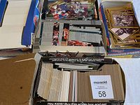 Box with a mix of assorted sports cards including football and basketball cards, some cards visible showing player stats and images.