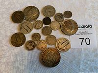 Photo showing various US silver coins spread on white cloth including half dollars, dimes, and other denominations with visible wear and tarnish.