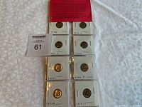 Photo of the 8 brilliant uncirculated Roosevelt dimes placed in individual holders, arranged in two columns on a white surface with a lot number card.