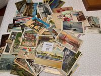 Photo showing a wide assortment of postcards spread out including scenic views, floral images, and some with visible handwriting