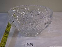 Clear Bohemian crystal bowl viewed from the side showing detailed cut patterns and a measuring tape indicating approx. 8 inches in diameter.