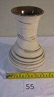 Front view of handcrafted ceramic vase showing shape, color pattern, and approximate dimensions with measuring tape at base.