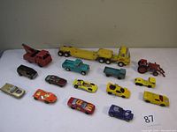 Overview of 15 assorted metal toy cars showing varying vehicle types and colors with some missing parts and wear.