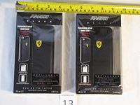 Two unopened boxes of Scuderia Ferrari Black fragrance spray hard cases for iPhone 6 and 6s. Each box has a black hard case with yellow Ferrari logo, 0.8 fl.oz refillable perfume spray.