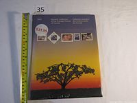Front cover of the sealed souvenir collection booklet featuring a tree at sunset and sample stamps with Canadian themes.