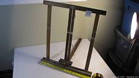 Wooden easel standing upright showing front and side structure with ruler for scale.