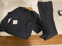 Navy blue women's pant suit laid flat consisting of jacket and pants, showing suit color and fit size label 38 (likely European size 8).