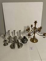 Photo showing all items in the lot arranged including kerosene lamp, candlesticks, candelabra, and bookends