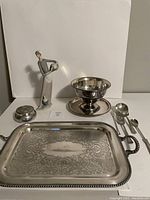Photo showing all items including figurine, metal bowl with saucer, metal tray, covered jar, and serving utensils arranged together