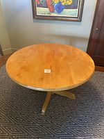 Top view of round maple pedestal table showing wood surface and finish.