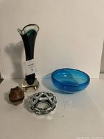 Photos show four items: tall dark green crystal vase, bright turquoise blue bowl, small clear crystal ashtray, and small wood carved piece, all arranged on white background.