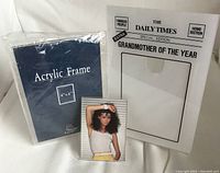 Photo showing all three acrylic photo frames: The Daily Times Grandmother of the Year frame, 4x6 frameless acrylic frame in packaging, and a wallet-sized frame with a photo inserted.