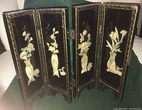 Pair of black lacquered Asian-style mini folding room dividers with gold floral motifs and 3D floral vase art on inside panels shown partially open