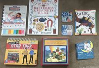 Photo of all seven children's books and two coasters arranged on a surface showing front covers and titles.