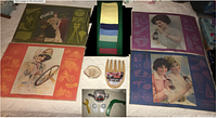 Four vintage Coca-Cola placemats, colored linen napkins, wooden salad paws, shell party picks in clamshell, and kitchen gadgets laid out for display.