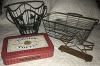 Full view of four items: green wire basket with metal ivy and wood vine, chrome rectangular basket with spun handle, brown metal star on base, English Toffee tin