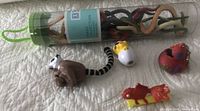 Photo showing all 5 small toy animals: sealed snake collection tube, plastic lemur, orange goldfish, baby duck with sunglasses, and paint-splattered rubber duck keychain.