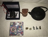 Full view of all six items including teapots, figurines, and napkins arranged on a white surface