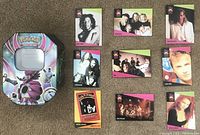 Top view showing front of 9 ProSet MusiCards featuring different music artists and Pokemon Trading Card tin with artwork.