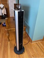 Front angle view of the Bionaire tower fan showing body, base, and cord on wooden floor.