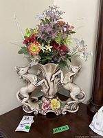 Full view of the Capodimonte ceramic urn with two rearing horses holding the central vase, filled with mixed faux flowers