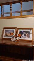 Photo showing a Gremlins Mogwai Gizmo plush with large ears and two Disney Lady and the Tramp framed prints on a wooden surface under a wooden railing.