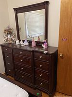 Front view of wooden dresser with 12 drawers and decorative items on top.