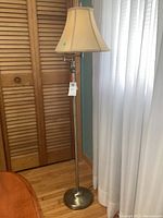 Full view of the floor lamp showing the brass look metal base, long pole, and swing arm.