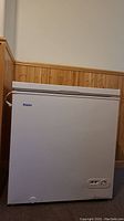 Front view of white Haier chest freezer with control panel and power cord unplugged.