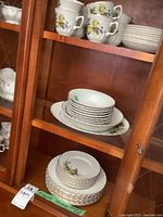 Ironstone dishes arranged on shelves showing plates, bowls, cups and saucers with yellow rose floral pattern and gold trim