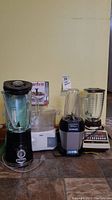 Photo showing the full lot with Ninja Professional blender (black & silver base), an extra blender carafe, vintage Osterizer blender with glass jar and black lid, Hamilton Beach metal mixer with manual, Oster food steamer and boxed Starfrit collapsible steamer.