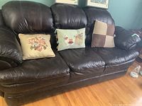 Front view of full leather sofa showing three-seat cushions and three decorative pillows